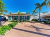 Charming tropical property featuring palm-lined entrance and brick driveway leading to your coastal retreat.