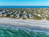 Aerial view of beachfront community with pristine white sand and turquoise waters stretching along the coastline.