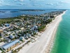 Stunning aerial view of a pristine beachfront community with turquoise waters, white sand beach, and colorful coastal homes.