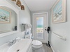 Your coastal-themed bathroom features ocean artwork and a window revealing stunning beach views during your stay.