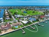 Aerial view of a waterfront property with private dock access, nestled in a coastal golf community surrounded by scenic waterways and lush fairways.