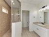 The spacious bathroom features elegant stone tiles, a walk-in shower with glass doors, and a stylish vanity with ample counter space for your morning routine.