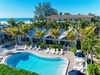 Beachfront resort with tropical landscaping, multiple buildings, and pristine blue ocean views.