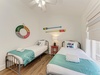 Two cozy beds await, adorned with crisp linens and cheerful nautical touches. Vaulted ceilings and natural light create a bright, breezy retreat for restful mornings and peaceful nights.
