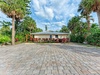Tropical vacation home nestled among swaying palms and vibrant landscaping with convenient paved parking.