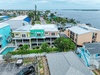 Waterfront vacation rental community featuring colorful coastal homes with direct water access, private docks, and palm-lined streets overlooking calm bay waters.