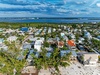 Aerial view of a tropical coastal community with colorful beach houses nestled among palm trees, offering easy access to pristine waters.