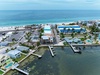 Aerial view of a coastal vacation property featuring private boat docks, waterfront homes with pools, palm-lined streets, and direct access to pristine white-sand beaches and turquoise Gulf waters.