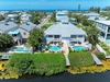 Aerial view of a coastal rental property featuring private pools, lush tropical landscaping, and direct waterfront access just steps from the beach.