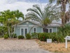 Charming coastal cottage featuring classic beach-style architecture, lush tropical landscaping, and a private paver driveway at the entrance to this tranquil island retreat.