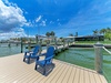 A private waterfront dock featuring boat slips and blue Adirondack chairs along a canal-side property in a tropical neighborhood setting.