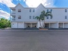 Modern multi-unit property with convenient ground-level parking and tropical landscaping under clear blue skies.
