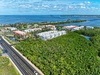 Aerial view of waterfront property nestled between tropical vegetation and pristine coastline with easy highway access.
