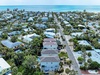 Aerial view of a charming coastal neighborhood with colorful homes, palm trees, and pristine turquoise waters just steps away.