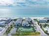Aerial view of beachfront vacation rental community with tennis court, pool, and direct beach access on pristine white sand coastline.