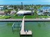 Aerial view of waterfront property featuring a private dock on a tranquil canal, surrounded by lush tropical landscaping in a peaceful residential neighborhood with convenient water access.