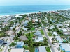 Aerial view capturing a vibrant beachside neighborhood nestled between residential streets and pristine white sand beaches along turquoise Gulf waters.