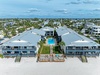 Beachfront resort complex featuring two symmetrical buildings with swimming pools and beach access in a coastal community setting.