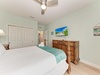Step into your serene coastal bedroom, where soft mint walls and beachy decor create a calming oasis. Relax under the ceiling fan on plush bedding while watching your favorite shows, with thoughtful touches and coastal charm surrounding you.