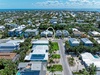Aerial view of a coastal neighborhood featuring the circled rental property, nestled among palm-lined streets with easy access to beautiful blue waters and sandy beaches nearby.