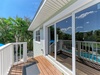 Bright balcony overlooks a sparkling pool and lush tropical greenery—your private retreat for morning coffee or evening relaxation under clear blue skies.