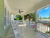 Relax on your covered balcony with rocking chairs and ceiling fan, overlooking lush palms and tropical surroundings.