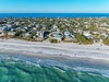Stunning aerial view of beachfront neighborhood with pristine white sand beach and crystal-clear turquoise waters.