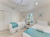 Rest peacefully in your twin bedroom featuring crisp white linens, coastal accents, and a ceiling fan for comfort.