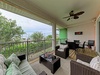 Your private outdoor living space features a breezy ceiling fan, plush seating for lounging, and a dining set for alfresco meals, all overlooking lush tropical greenery.