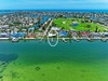 Aerial view of a waterfront community with a private dock, golf course views, and ocean access in a sunny coastal neighborhood.