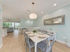 Step into your bright, airy dining space where soft aqua walls and warm hardwood floors create a coastal calm. Gather around the pristine white table under elegant lighting and savor meals with garden views beyond.