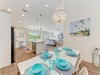 Gather around this sun-filled dining space where coastal charm meets comfort. Enjoy meals at the elegant table under a stunning chandelier, with the open kitchen and living area creating a perfect flow for your stay.