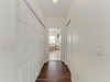Clean hallway with ample storage connects your private bedroom area to a bright bathroom beyond, featuring warm hardwood floors and fresh neutral tones.