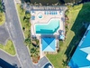 Aerial view of waterfront property featuring a sparkling swimming pool, hot tub, and direct beach access in a peaceful residential neighborhood.