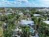 Aerial view of tropical neighborhood showcasing lush palm trees and colorful residential homes under bright blue skies.