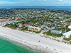 Aerial view of pristine white sand beach and turquoise waters with beachfront vacation rental properties scattered throughout the coastal community.