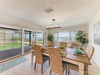 Gather around this welcoming dining table where coastal breezes meet indoor comfort. Your mornings start with ocean views through expansive windows, while open doors invite seamless indoor-outdoor living.