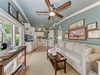 Your coastal-inspired retreat flows seamlessly from living to dining to kitchen, with gentle ceiling fans, soft natural light, and nautical artwork creating a breezy, relaxing atmosphere.
