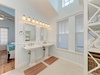 Indulge in this elegant dual-sink bathroom where coastal charm meets modern comfort, featuring luxurious lighting and plenty of space for your morning routine.