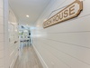 Step into your coastal retreat through this welcoming hallway, where charming shiplap walls and the cheerful 'Beach House' sign set the tone for your relaxing getaway.