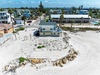 Aerial view of beachfront vacation homes nestled along pristine sandy shores in a charming coastal community.