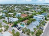Aerial view of a coastal vacation property nestled in a tropical neighborhood with palm trees, a private pool, and waterfront access nearby.