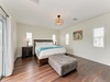 Sink into the plush king bed under a charming vintage-style pendant light, where coastal breezes drift through glass doors and warm wood floors anchor your serene tropical retreat.