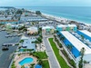 Aerial view of the coastal property location showcasing proximity to white sand beaches, waterfront marina access, and vibrant townhomes in a tropical beachside community.
