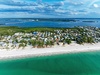 Aerial view showcasing the pristine beachfront location with turquoise waters and white sand beach stretching along the coastline.
