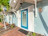 Charming beach cottage entrance with tropical palms and bright blue accents welcomes you to your coastal getaway.