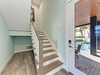 Step into your coastal retreat where elegant hardwood stairs meet pool access. Your private oasis awaits just beyond the glass doors.