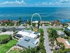 Aerial view of a waterfront vacation property located in a serene coastal neighborhood, surrounded by palm trees and offering direct access to the turquoise bay.