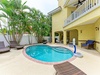 A tropical private pool area surrounded by lush palms, loungers for soaking up the sun, and covered patio seating—your own secluded outdoor escape.