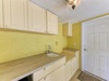 This sunny utility space features white cabinetry and a convenient sink, offering you practical storage and easy cleanup during your stay.